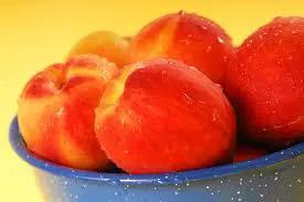 Ripe peaches in a blue speckled bowl on a yellow background